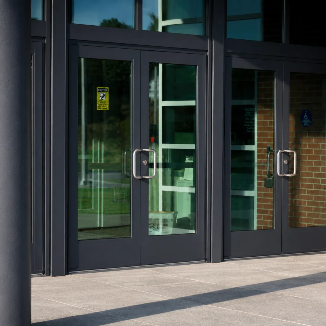 Commercial deadbolt lock cylinder in an aluminum glass storefront door with key in the cylinder