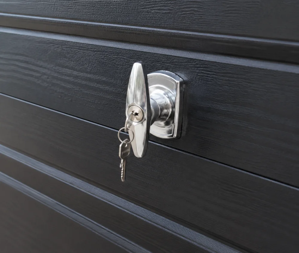 Chrome T-handle lock with keys on a black garage door