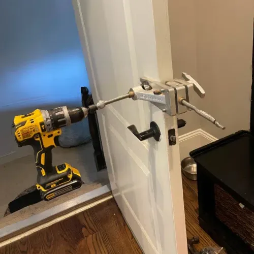 Bore jig and drill mounted on a white interior door for deadbolt installation