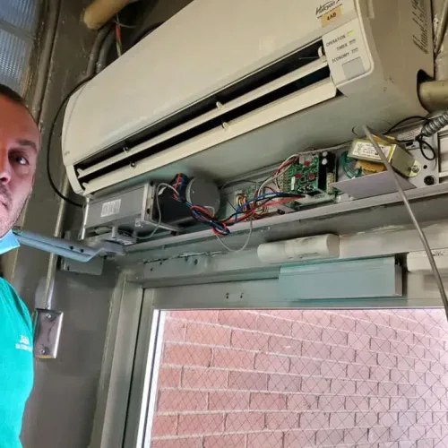 J&M Locksmith technician installing an automatic door opener control board above a commercial entrance